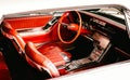Closeup shot of steering wheel, seats, doors, and dashboard in red and chrome classic car