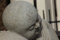 Closeup shot of a stone figure statue of a boy in a sitting position with closed eyes Royalty Free Stock Photo