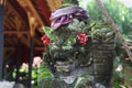 A closeup shot of a stone statue in Indonesia traditionally decorated with fabrics and flowers