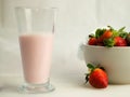 Closeup shot of strawberry milkshake and bowl of strawberries with white background