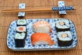 Closeup shot of sushi rolls in a plate next to chopsticks on a bamboo table cover Royalty Free Stock Photo