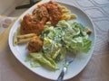 Closeup shot of tasty pasta with tomato meat sauce and fresh caesar salad on a white plate Royalty Free Stock Photo