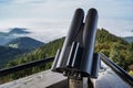 Closeup shot of a telescope and foggy hills with trees