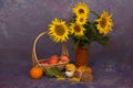 Closeup shot of a thatch basket with fruits near a pot with sunflowers in the studio Royalty Free Stock Photo