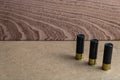 Closeup shot of three black shotgun ammo on a brown surface