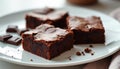 Closeup shot of three rich chocolate brownies on white plate with small pieces of dark chocolate. Crumbled cake bits on side Royalty Free Stock Photo