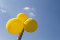 Closeup shot of three yellow balloons on a pole with a blue sky background Royalty Free Stock Photo
