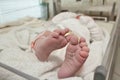 Closeup shot of tiny pair of feet and toes of newborn baby wrapped in a blanket wearing a plastic identity tag bracelet Royalty Free Stock Photo