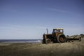Closeup shot of a tractor on the beach under the blue sky Royalty Free Stock Photo