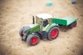 Closeup shot of a tractor toy on the sand in a playground during daytime Royalty Free Stock Photo