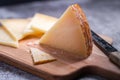 Closeup shot of triangle pieces of cured Manchego cheese and a sharp knife on a wooden food board