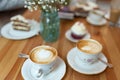 Closeup shot of two cups of cappuccino coffee with foam on a wooden table