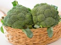 Closeup shot of two fresh broccoli placed in a basket placed in front of a white background Royalty Free Stock Photo