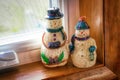 Closeup shot of two homemade snowman figures sitting on a windowsill