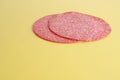 Closeup shot of two slices of salami on a yellow background