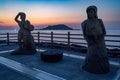 Closeup shot of two statues at Hyeopjae Beach with a sunset backdrop