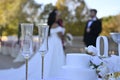 Closeup shot of two wedding champagne flutes on an outdoor table with a couple in the background Royalty Free Stock Photo