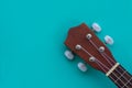 Closeup shot of a ukulele headstock on a turquoise background