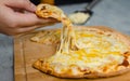 Closeup shot of unrecognizable unknown human hand picking up piece of delicious tasty double cheese traditional Italian crust thin
