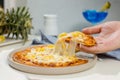 Closeup shot of unrecognizable unknown human hand picking up piece of delicious tasty Hawaiian traditional Italian crust thin