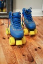 Closeup shot of vintage blue quad roller skates with yellow wheels on wooden floor