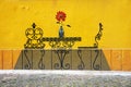 Closeup shot of wall art - a table with a red flower and two chairs on a yellow background Royalty Free Stock Photo