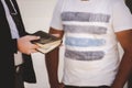 Closeup shot of a well dressed male holding the bible while talking to a person Royalty Free Stock Photo