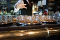 Closeup shot of whiskey glasses on metal trays in the bar with the barman on the background Royalty Free Stock Photo