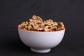 Closeup shot of a white bowl of nuts on a black background Royalty Free Stock Photo