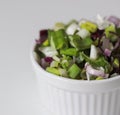 Closeup shot of a white bowl of a vegetable salad on a white surface Royalty Free Stock Photo