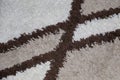 Closeup shot of a white fluffy carpet with brown crossing lines