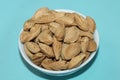 Closeup shot of a white round bowl of almonds in shells on a blue background