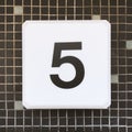 Closeup shot of a white sign with a black five number