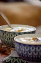 Closeup shot of white soup in a beautiful bowls with colorful patterns on a wooden table