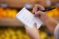 Ticking off her items as she goes along. Closeup shot of a woman checking her shopping list in a grocery store. Royalty Free Stock Photo