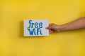 A closeup shot of a woman holding a paper with the word FREE WIFI on a yellow background Royalty Free Stock Photo