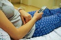 Closeup shot of a woman lying on an adjustable hospital bed while holding a remote control