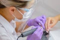 Closeup shot of woman in nail salon receiving manicure by beautician with nail file and machine. Woman getting nail Royalty Free Stock Photo