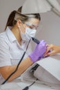 Closeup shot of woman in nail salon receiving manicure by beautician with nail file and machine. Woman getting nail Royalty Free Stock Photo