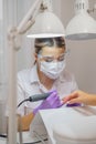 Closeup shot of woman in nail salon receiving manicure by beautician with nail file and machine. Woman getting nail Royalty Free Stock Photo