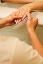 Closeup shot of a woman in a nail salon receiving a manicure by a beautician with nail file. Woman getting nail manicure Royalty Free Stock Photo