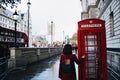 Closeup shot of a woman standing in front of the telephone booth in Great Britain