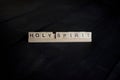 Closeup shot of a wooden blocks spelling holy spirit with a black background Royalty Free Stock Photo
