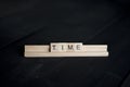 Closeup shot of wooden blocks spelling out time on a black wooden surface Royalty Free Stock Photo