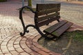 Closeup shot of the wooden broken bench with wrought iron legs near the sidewalk