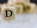 Closeup shot of a wooden cube with the letter D on a blurred background