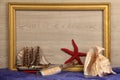 Closeup shot of a wooden frame, starfish, boat toy, seashell, and a bottle with writing \