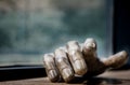Closeup shot of wooden human's hand on a table near the window with its shadow on blurry background