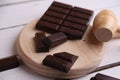 Closeup shot of a wooden small mallet near a bar of dark chocolate