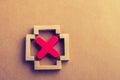 Closeup shot of a wooden square structure with a red X sign in it on a brown surface